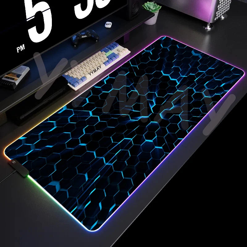 Gaming desk setup with a large illuminated mouse pad featuring a honeycomb pattern.