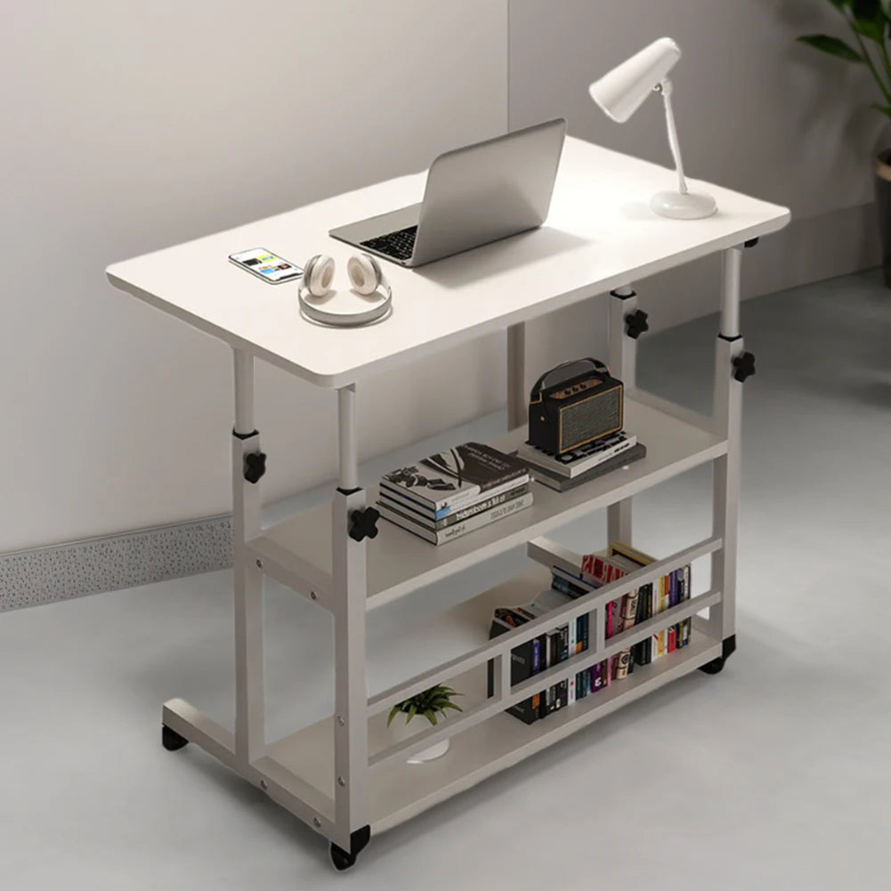 White adjustable desk with laptop, books, and lamp in a room setting