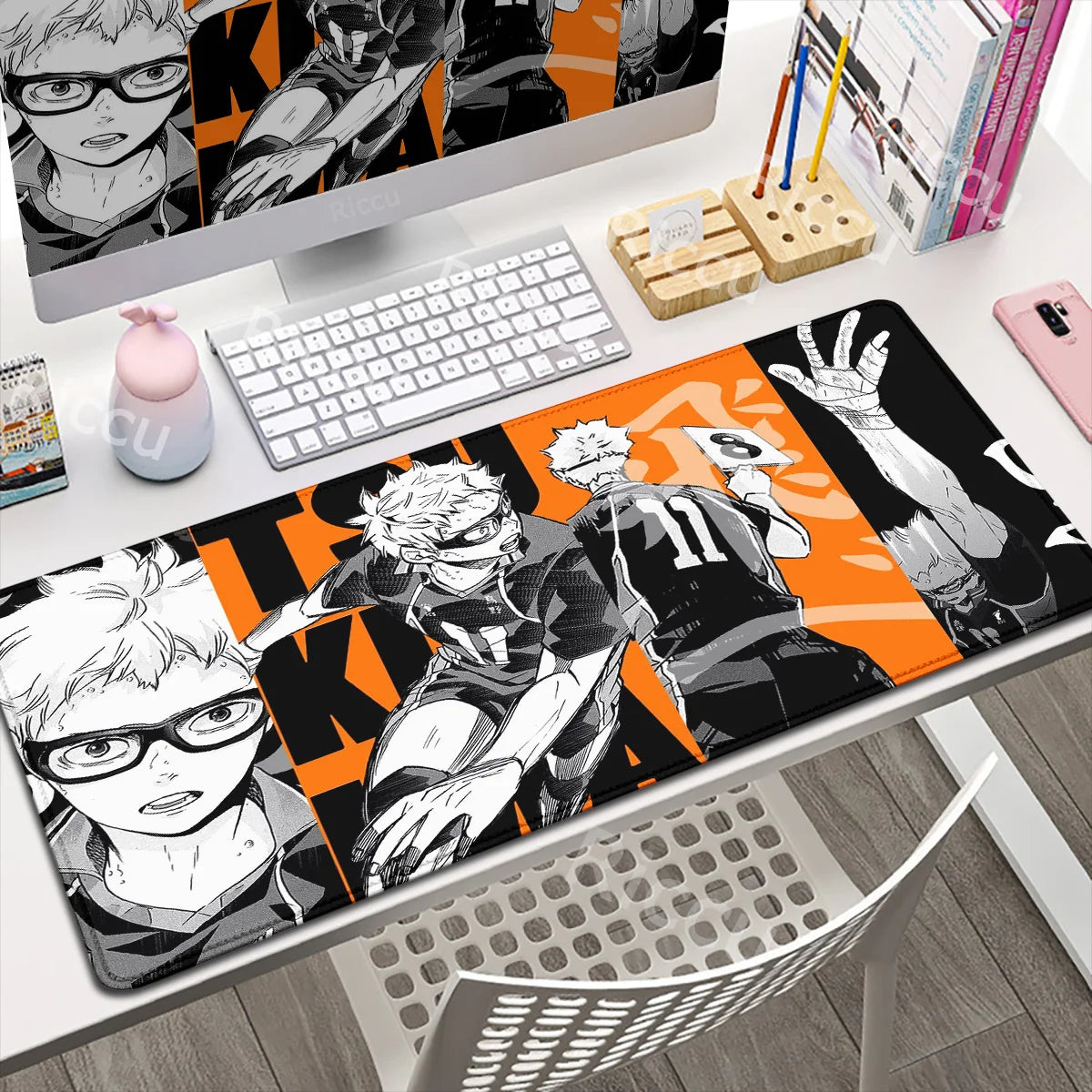 Desk setup with a large mouse pad featuring anime-style characters, keyboard, and computer monitor.