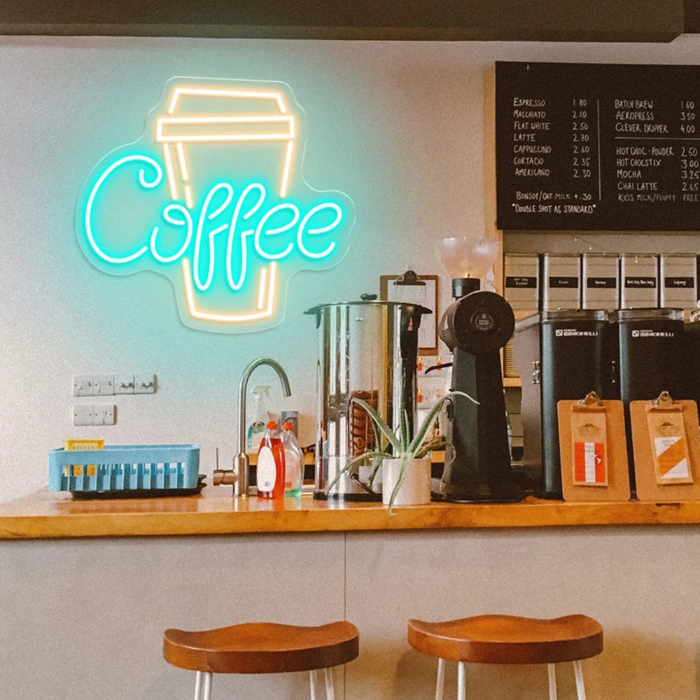 Neon coffee sign above a counter with coffee-making equipment and stools in a coffee shop.