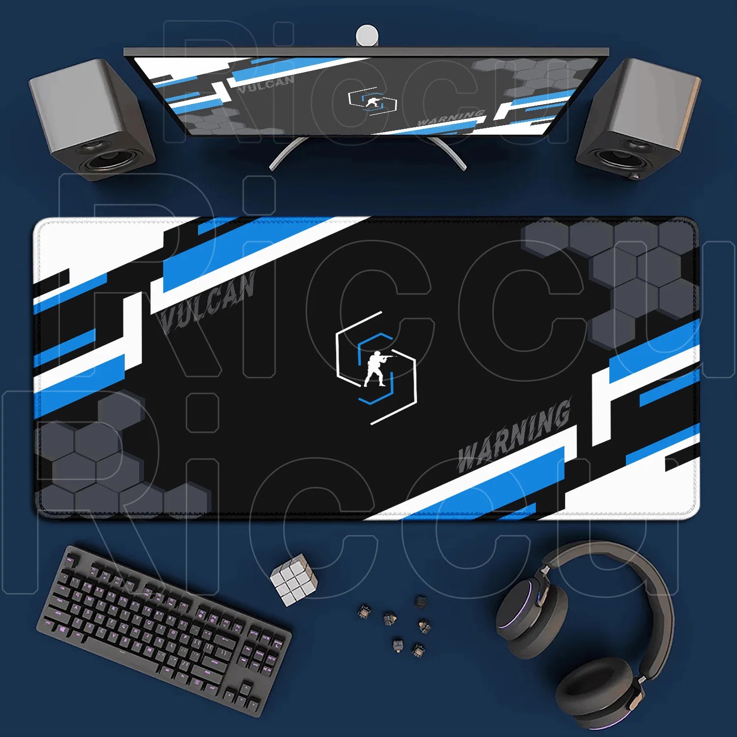 Gaming setup with monitor, mouse pad, keyboard, and headphones on a blue surface.
