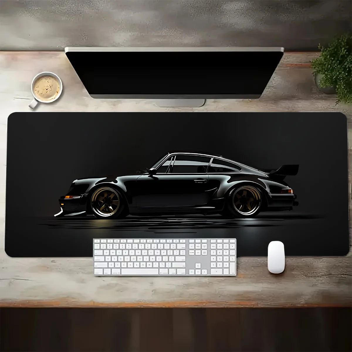 Black desk mat with a car design on a wooden desk with a computer setup.