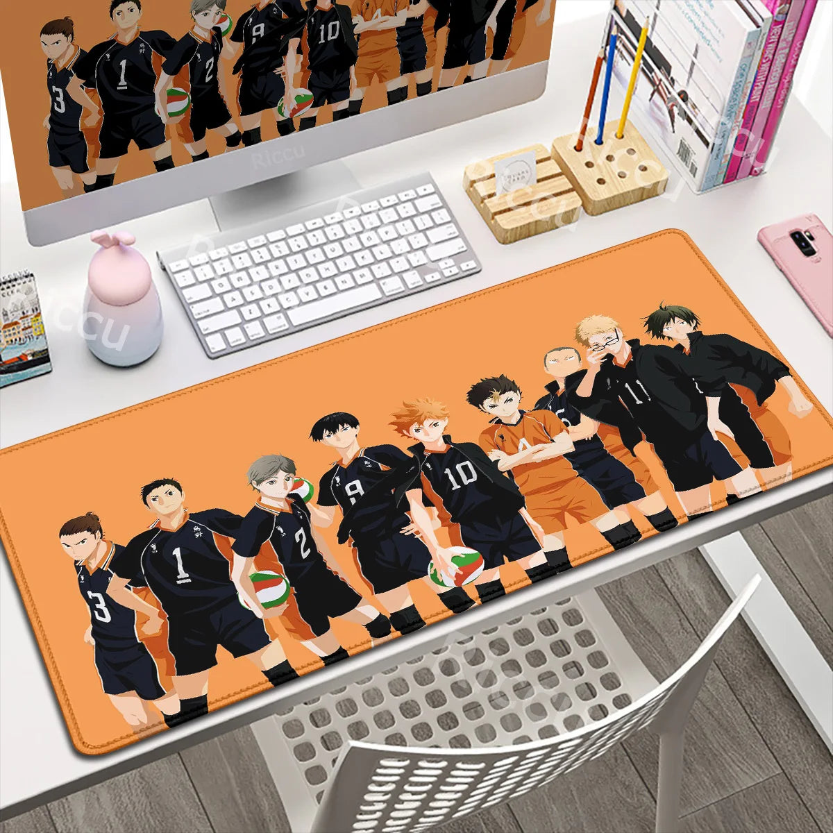 Desk setup with a computer monitor, keyboard, and mouse pad featuring anime characters.