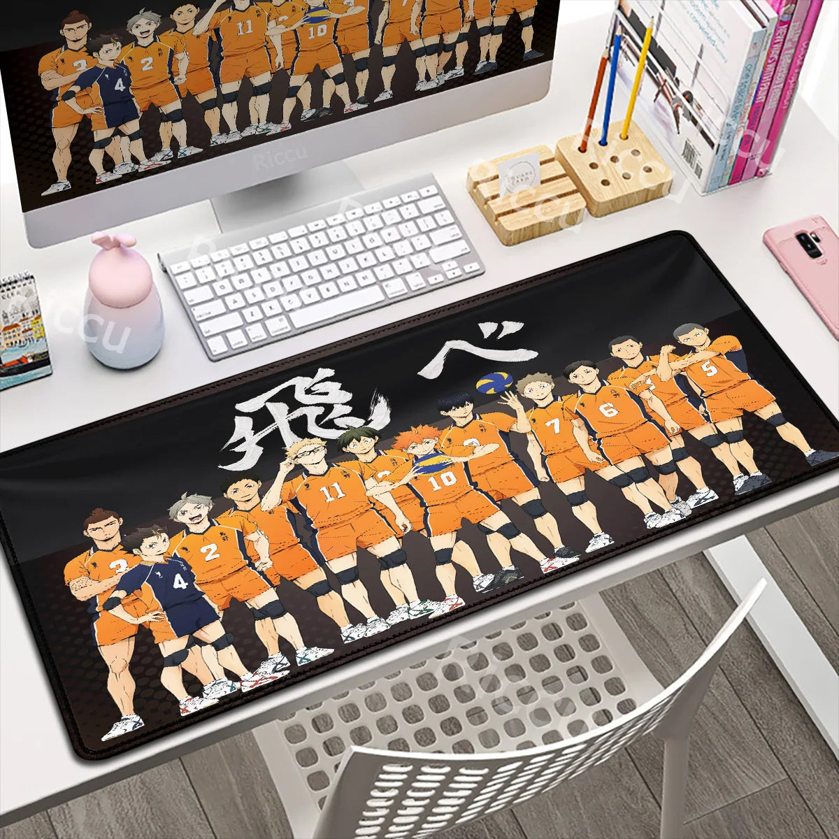 Desk setup with a large mouse pad featuring animated characters, keyboard, and monitor.