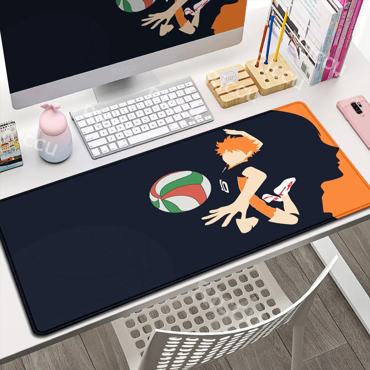 Desk setup with a large mouse pad featuring an anime character and volleyball, next to a computer monitor and keyboard.