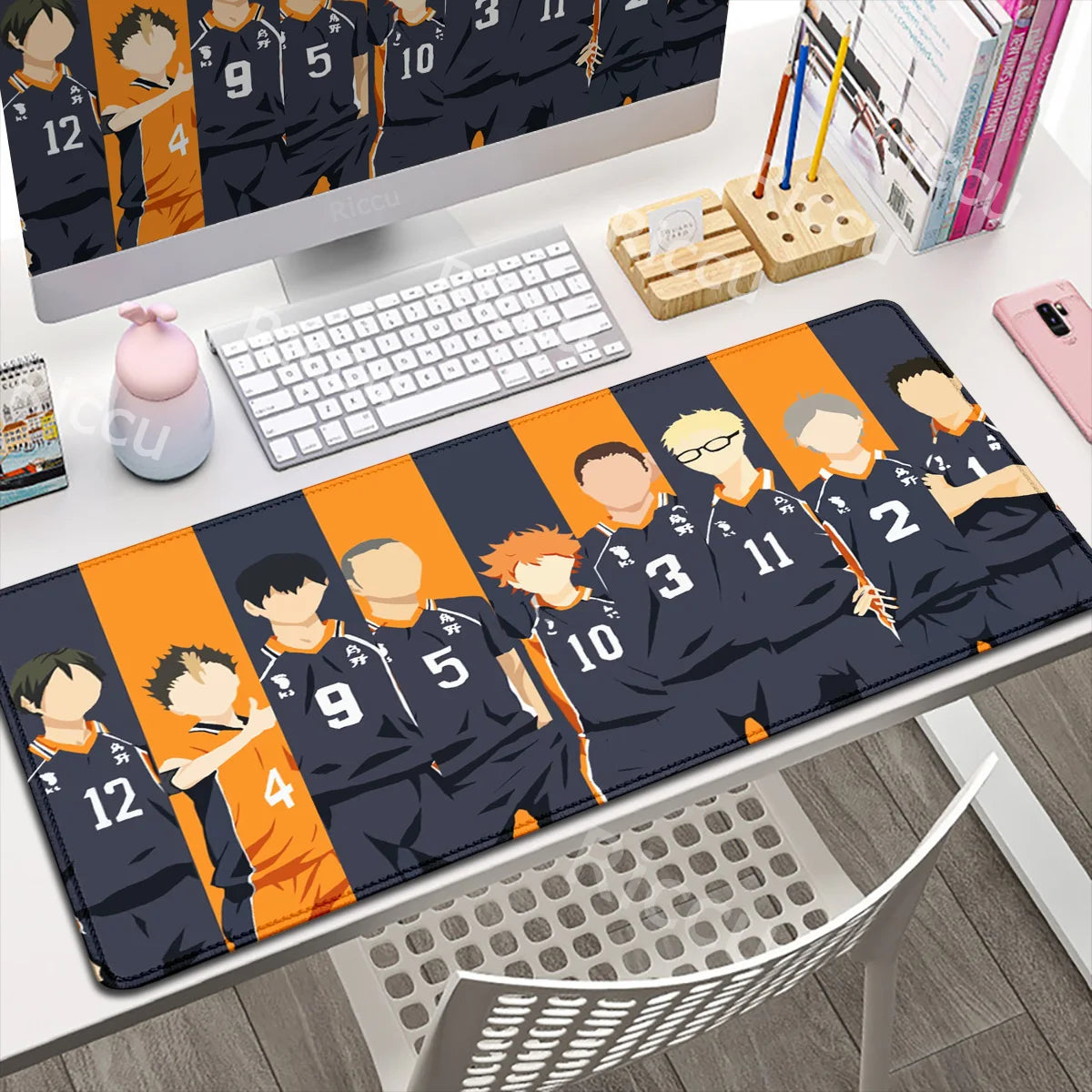 Desk setup with a large mouse pad featuring animated characters and sports jerseys.