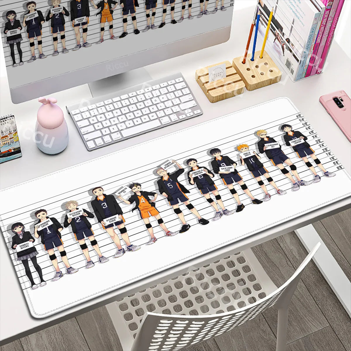 Desk setup with a large mouse pad featuring animated characters, keyboard, and monitor.
