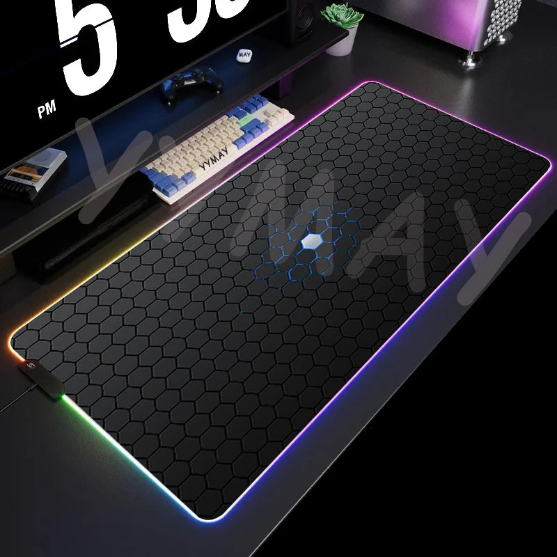 Gaming desk setup with a large black mouse pad featuring colorful LED lighting.