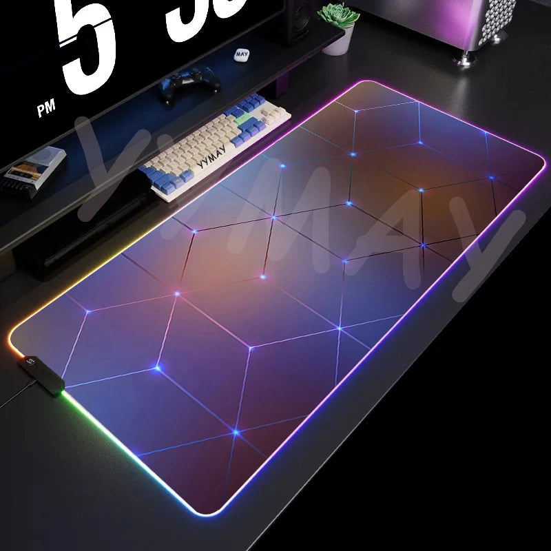 Gaming desk setup with a large illuminated mouse pad, keyboard, and computer monitor.