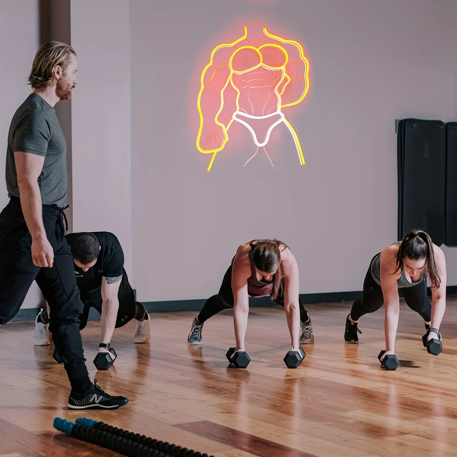 Group of people exercising in a studio with a neon sign on the wall.
