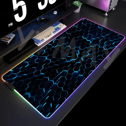Gaming desk setup with a large illuminated mouse pad featuring a honeycomb pattern.