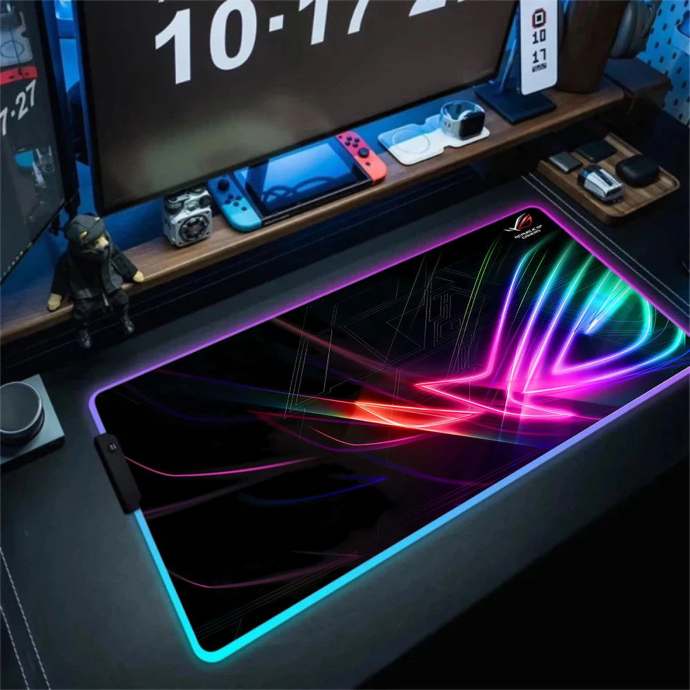 Gaming desk setup with a large RGB mouse pad, monitor, and gaming accessories.