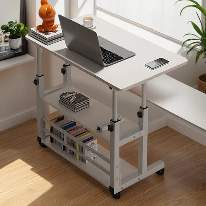 White adjustable desk with laptop, books, and a phone on a wooden floor.