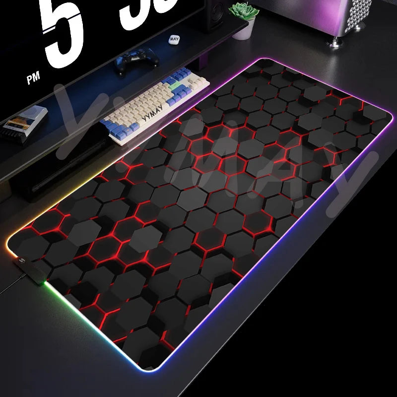 Gaming desk setup with a large hexagonal patterned mouse pad on a dark surface.