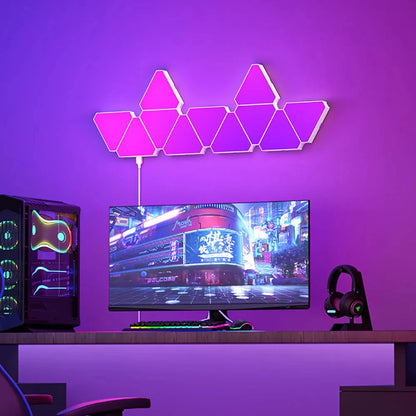 Neon triangular lights on a purple wall above a computer setup with a monitor, keyboard, and gaming chair.
