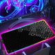 Gaming setup with a large mouse pad featuring a black geometric pattern, illuminated by colorful lights.