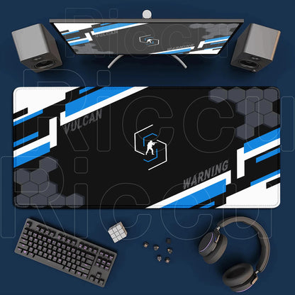 Gaming setup with monitor, mouse pad, keyboard, and headphones on a blue surface.