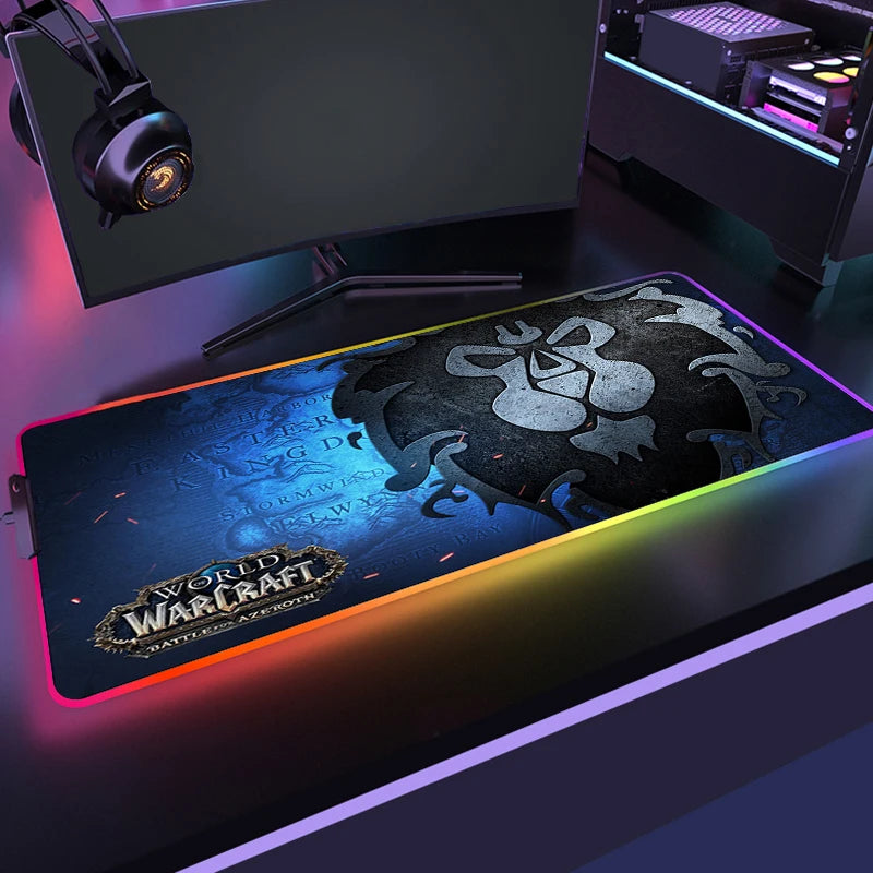 Gaming setup with a World of Warcraft mouse pad, monitor, and headphones on a dark surface.
