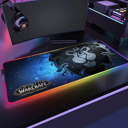 Gaming setup with a World of Warcraft mouse pad, monitor, and headphones on a dark surface.