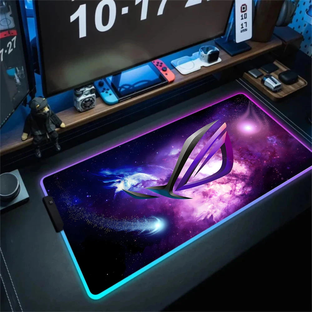 Gaming desk setup with a large mouse pad featuring a brand logo, surrounded by gaming accessories.