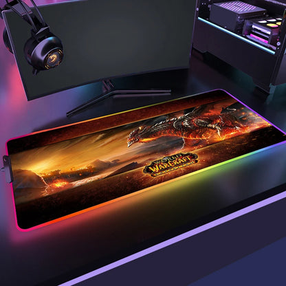 Gaming desk setup with a World of Warcraft mouse pad, monitor, and headphones.