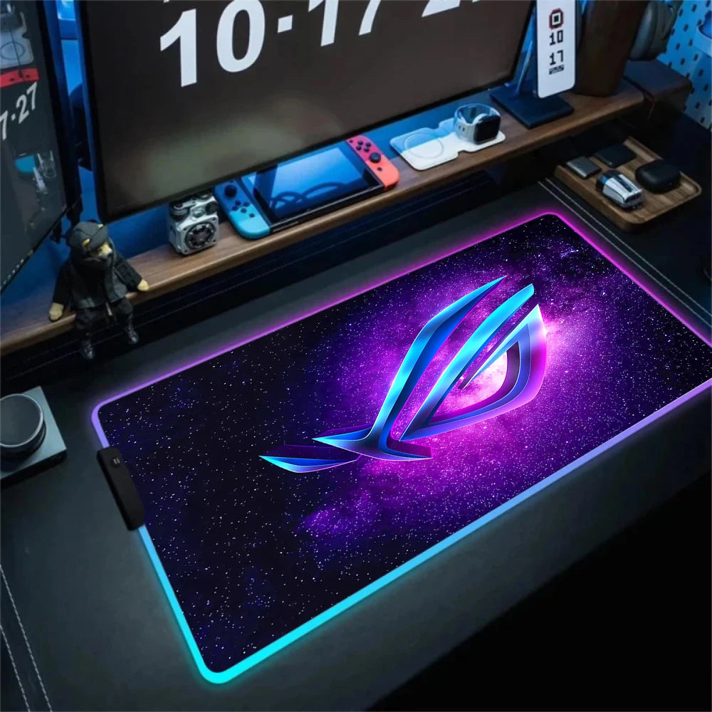 Gaming desk setup with a large mouse pad featuring a logo on a dark surface.