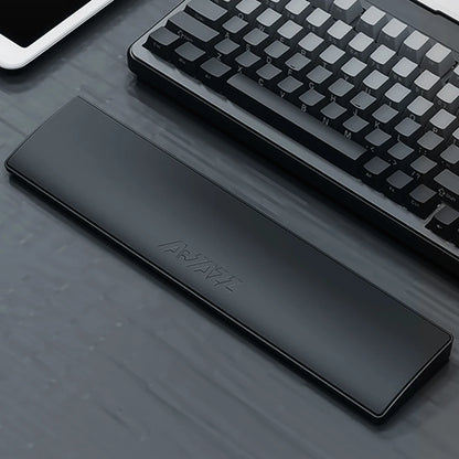 Black wrist rest on a desk with a keyboard and tablet in the background