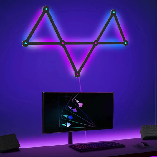 Neon triangle light fixture above a computer monitor on a desk with a purple background