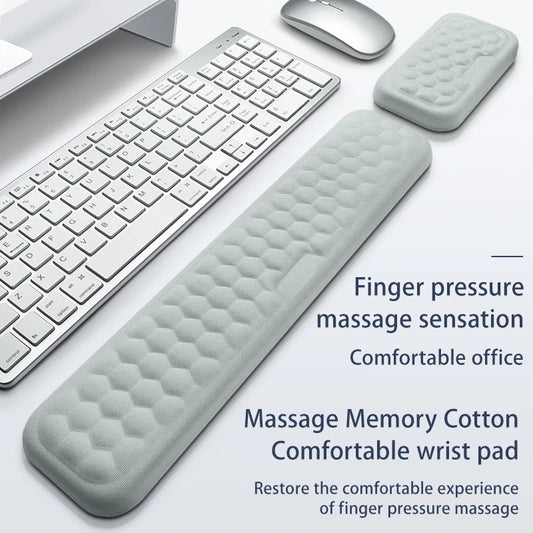 Gray wrist pad on a desk with keyboard and mouse, text about massage sensation and comfort.