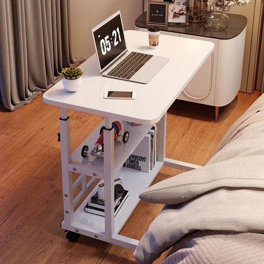 White adjustable desk with laptop, phone, and small plant in a room setting.