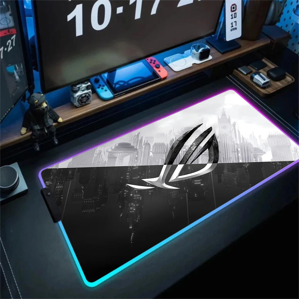 Gaming desk setup with a large mouse pad featuring a logo, multiple monitors, and gaming accessories.