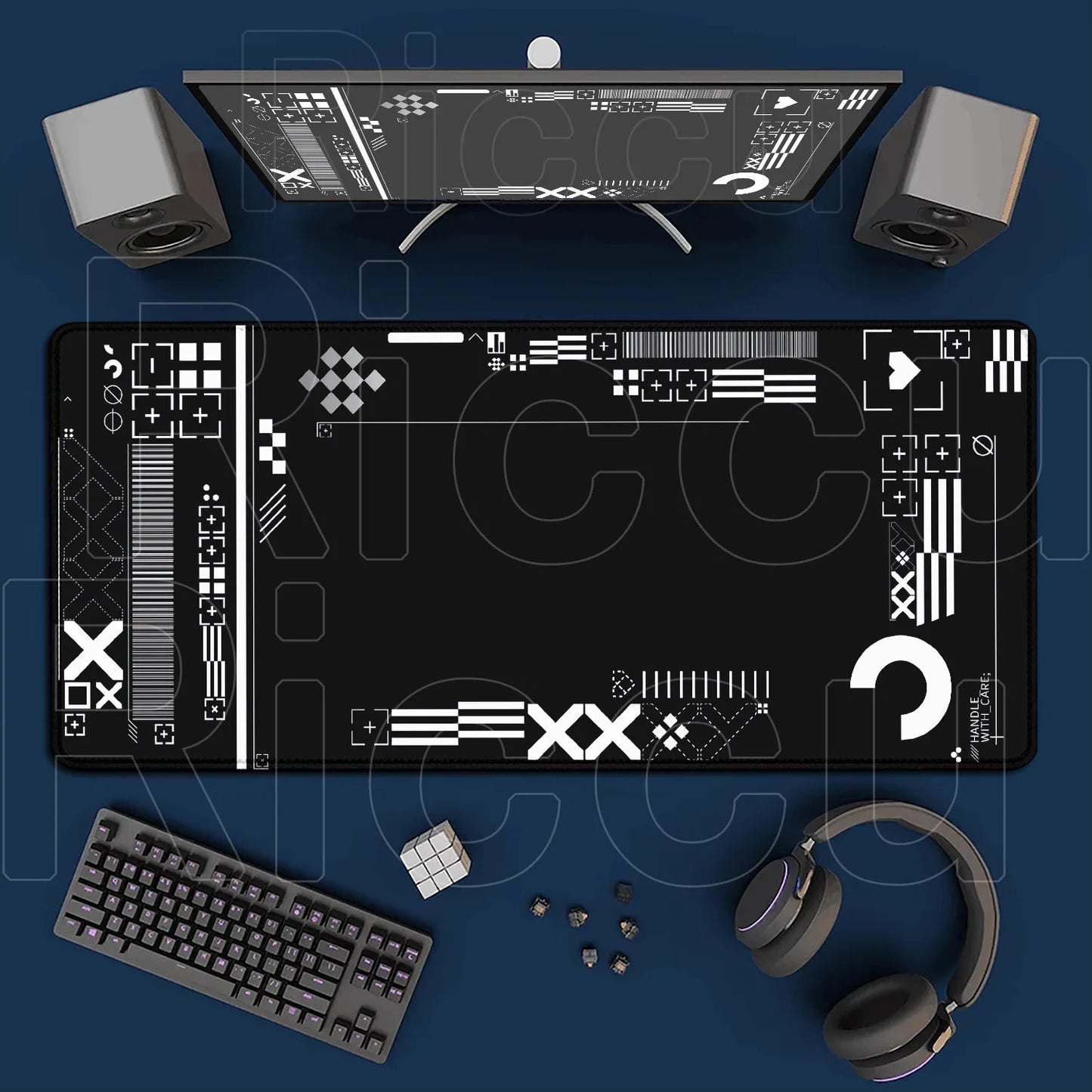 Top-down view of a desk setup with a computer monitor, keyboard, speakers, and headphones on a blue surface.