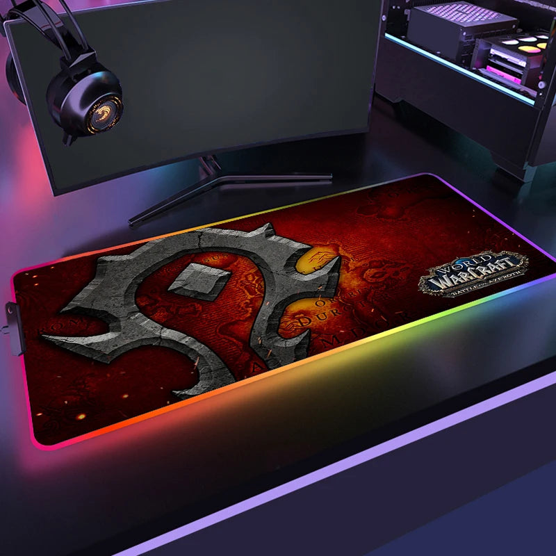 Gaming setup with a World of Warcraft mouse pad, monitor, and headphones on a desk.