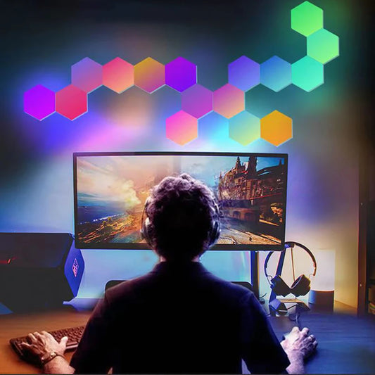 Person sitting at a desk with a computer monitor, surrounded by colorful hexagonal lights on the wall.