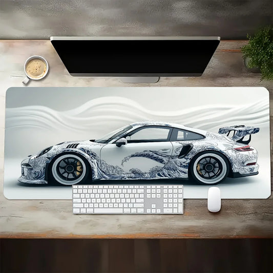 Desk setup with a large mouse pad featuring a car design, keyboard, and mouse.